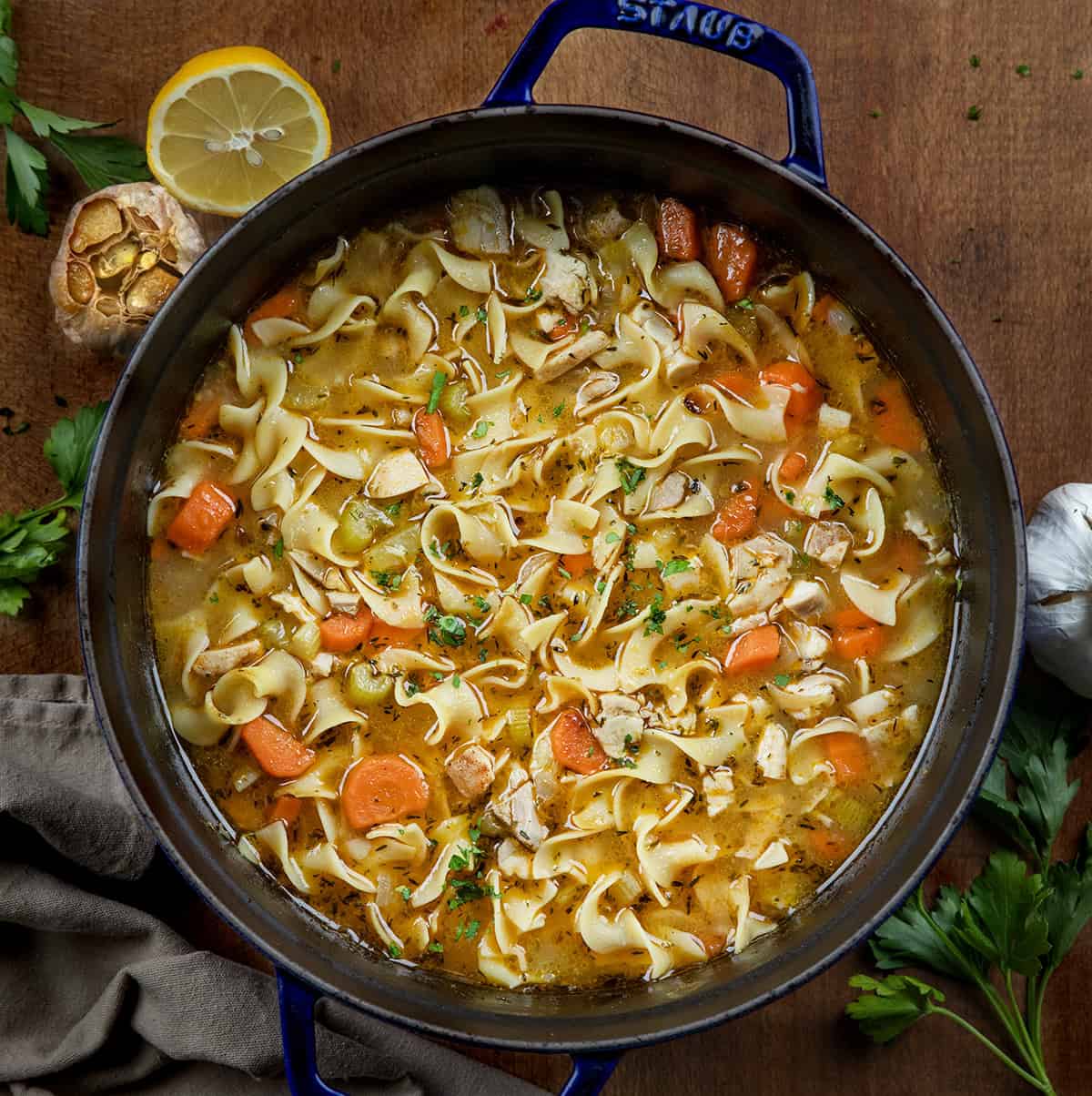 Pot of Roasted Garlic Chicken Noodle Soup on a wooden table from overhead Pot of Roasted Garlic Chicken Noodle Soup on a wooden table from overhead.
