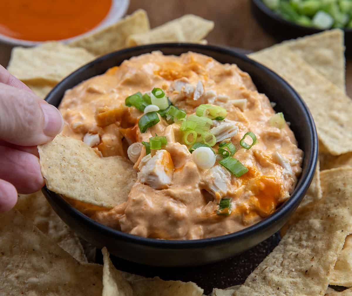 Hand dipping a chip into Slow Cooker Buffalo Chicken Dip Hand dipping a chip into Slow Cooker Buffalo Chicken Dip.