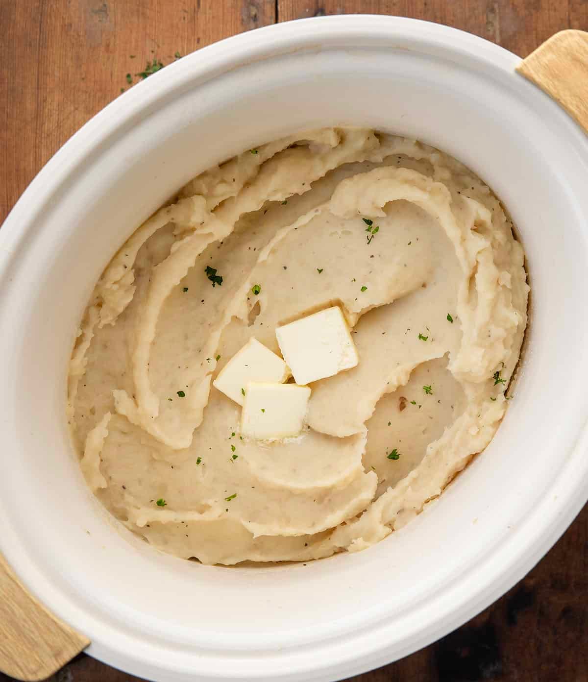 Slow Cooker Mashed Potatoes on a wooden table from overhead Slow Cooker Mashed Potatoes on a wooden table from overhead.