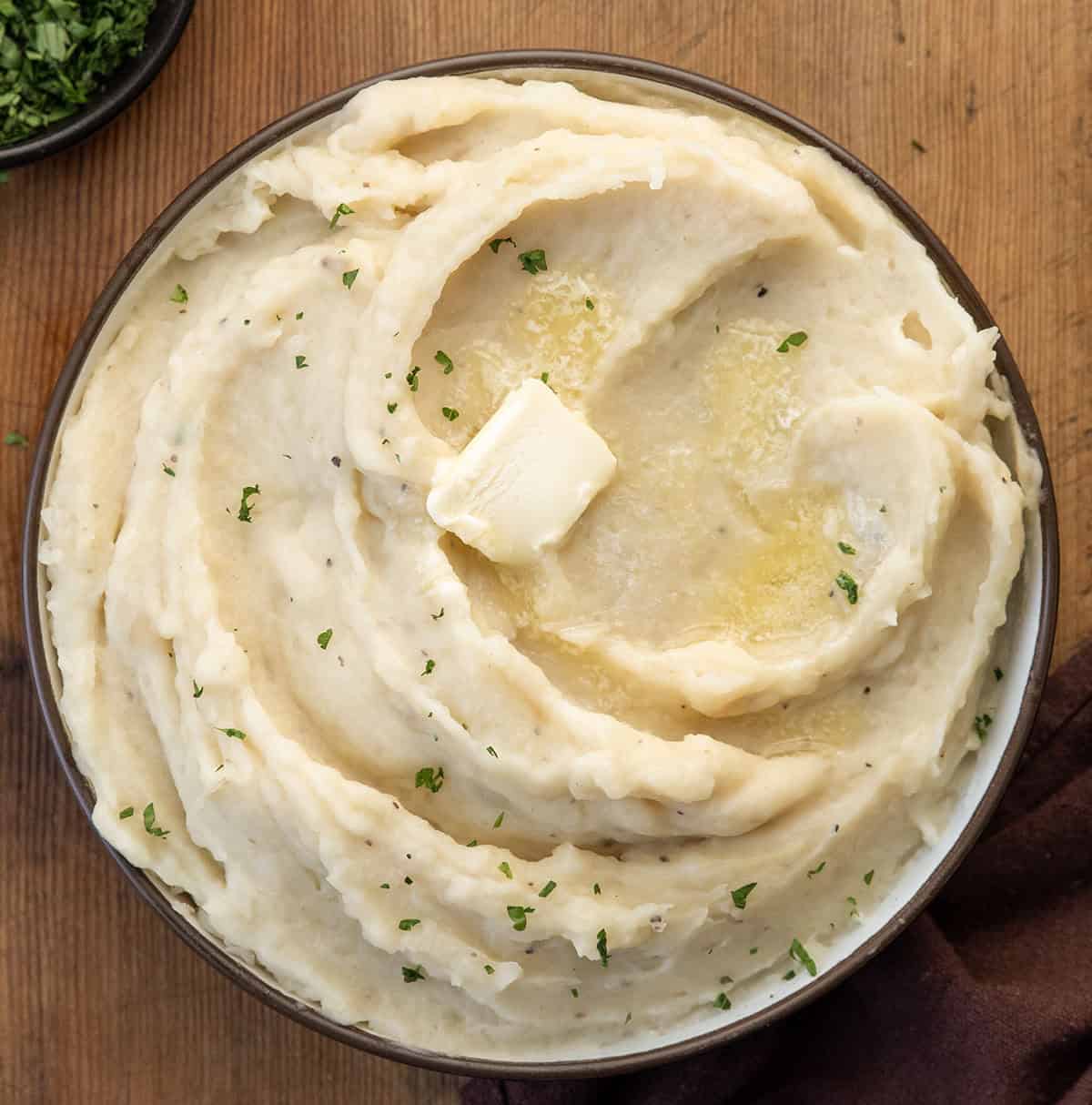 Bowl of Slow Cooker Mashed Potatoes with butter melting on it from overhead Bowl of Slow Cooker Mashed Potatoes with butter melting on it from overhead.