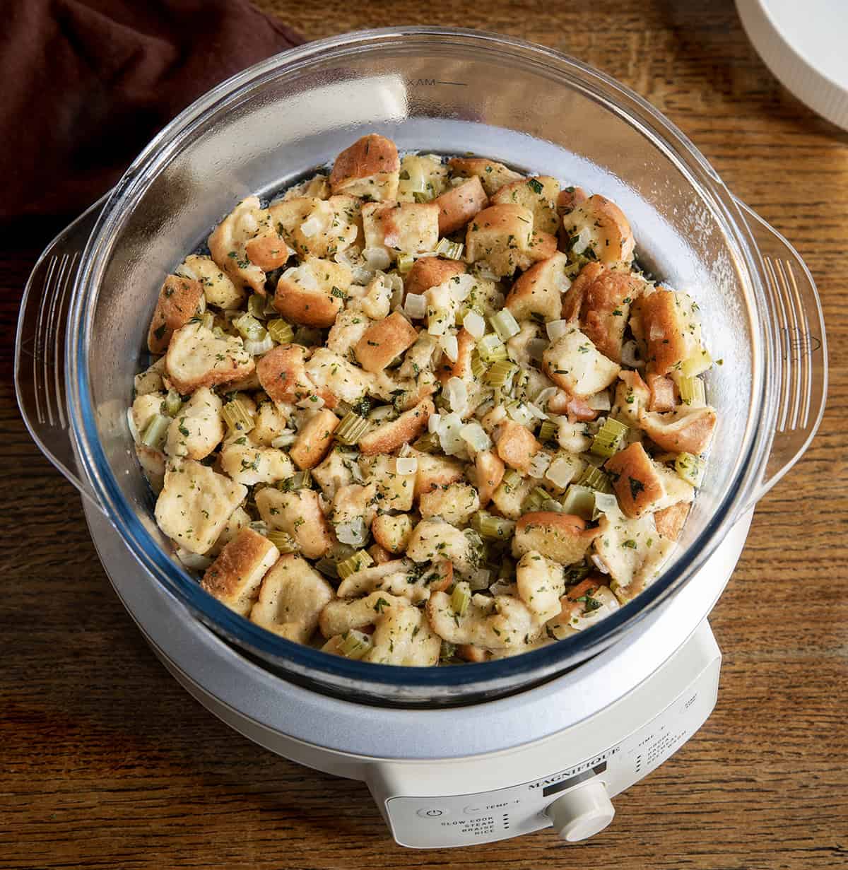 Crockpot of stuffing on a wooden table Crockpot of stuffing on a wooden table.